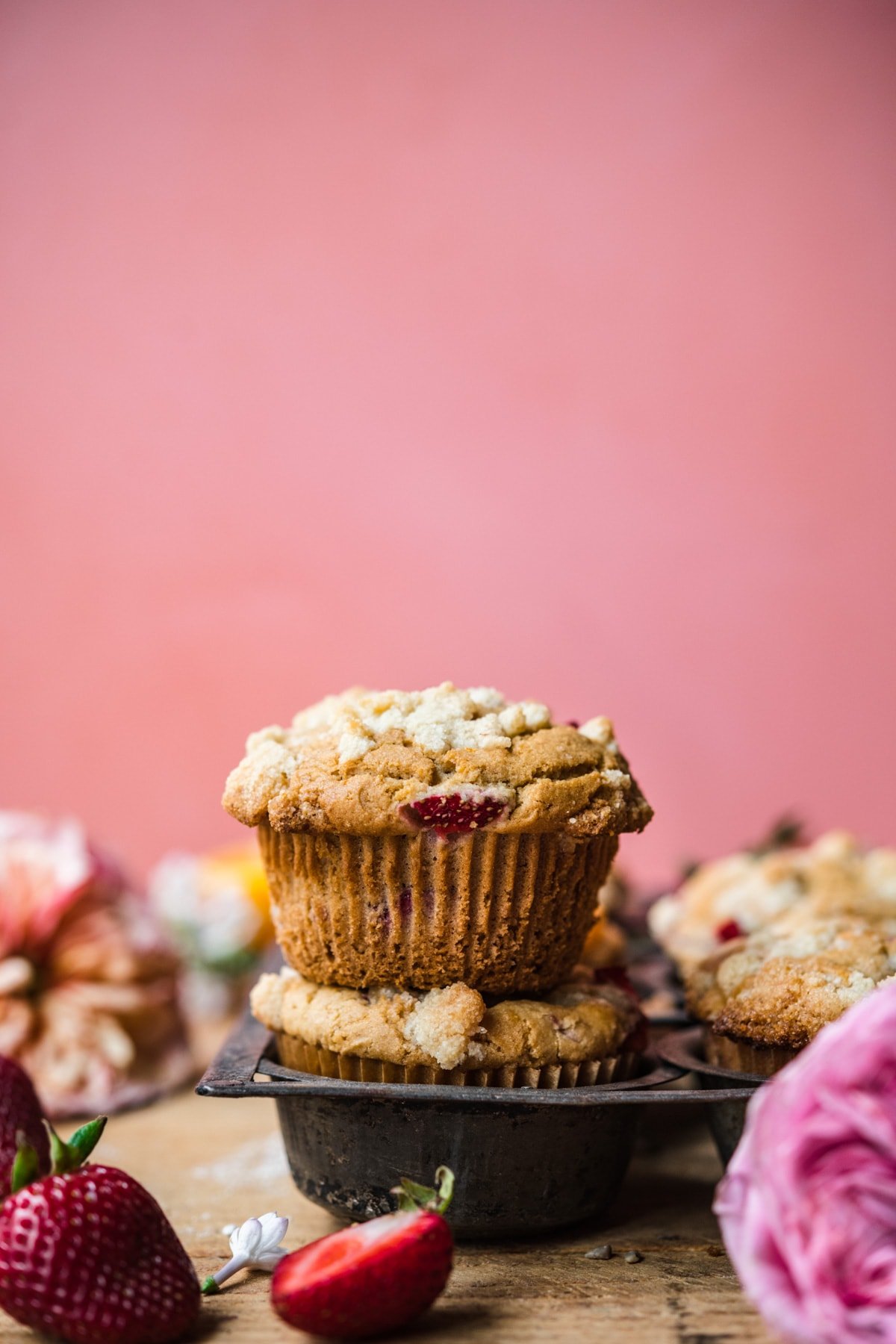 side view of two stacked vegan strawberry muffins with pink backdrop. 