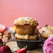 side view of two stacked vegan strawberry muffins with pink backdrop.