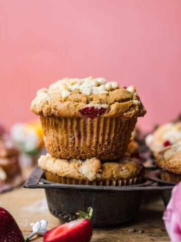 side view of two stacked vegan strawberry muffins with pink backdrop.