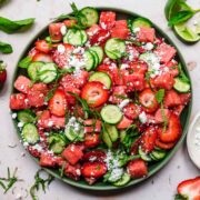 close up overhead view of watermelon cucumber strawberry salad on a plate with mint and feta.