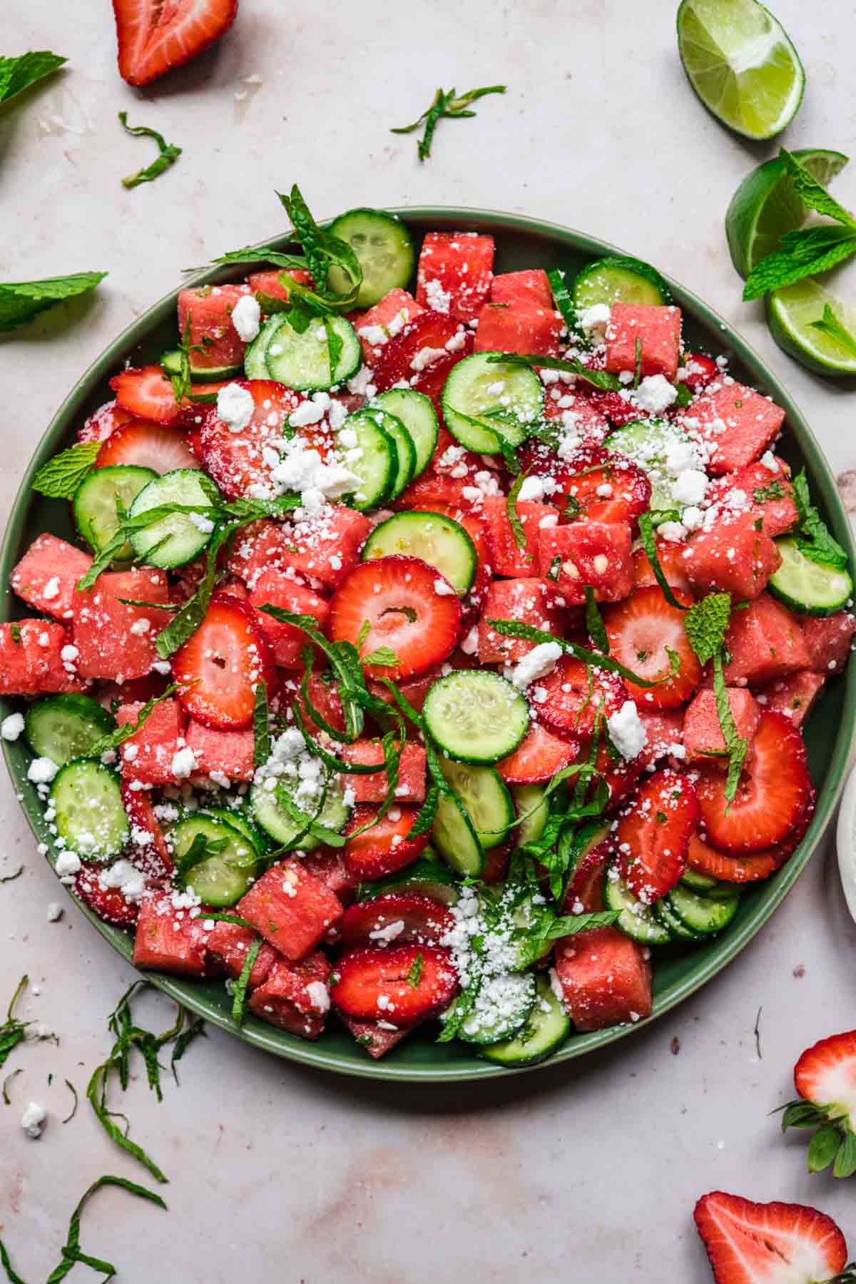 close up overhead view of watermelon cucumber strawberry salad on a plate with mint and feta. 