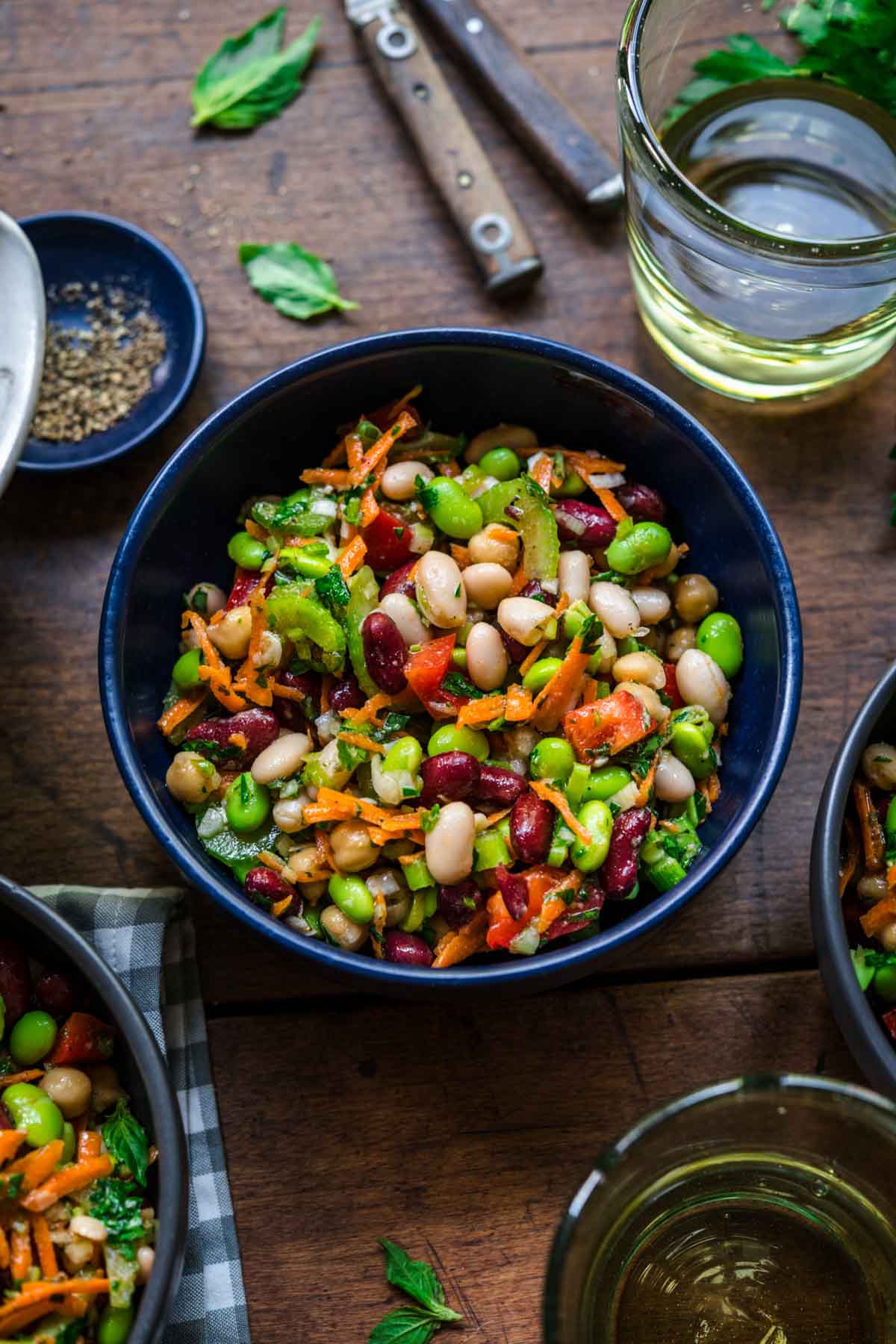 close up view of four bean salad in a blue bowl on wood table. 