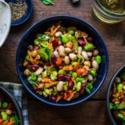 close up view of four bean salad in a blue bowl on wood table.