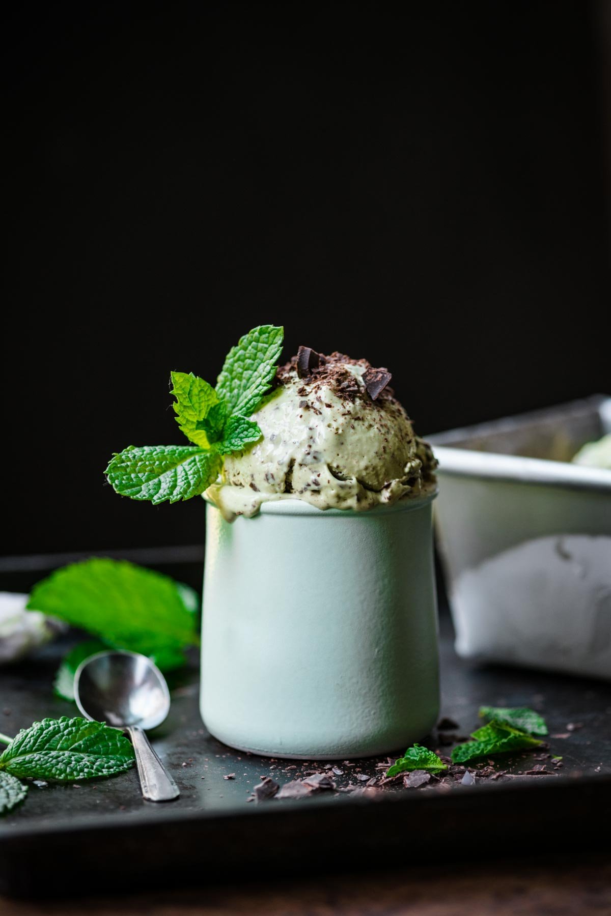 close up view of vegan mint chocolate chip ice cream in small jar with fresh mint on top. 