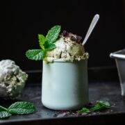 close up view of vegan mint chocolate chip ice cream in small jar with fresh mint on top.