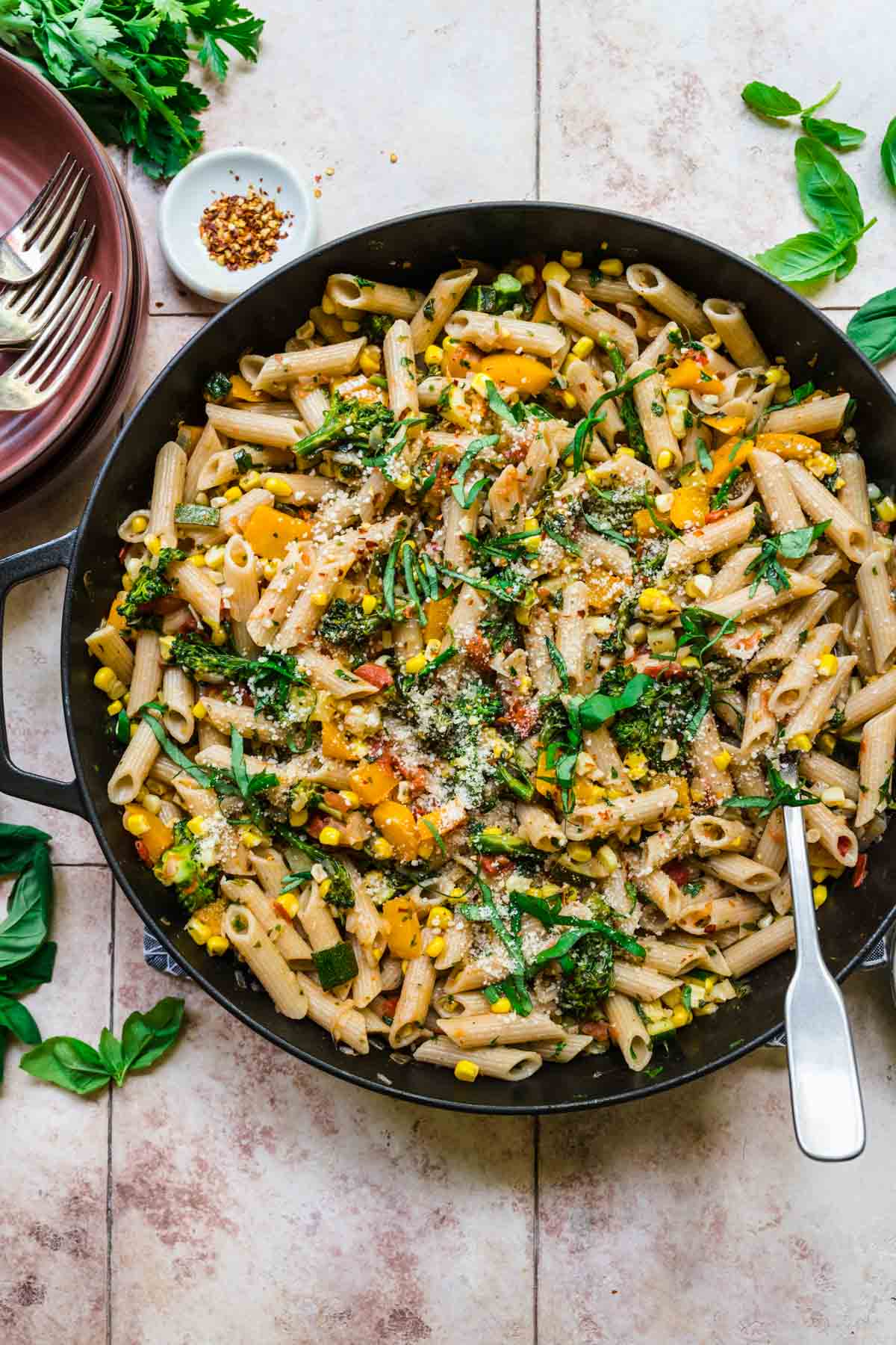 overhead view of vegan pasta with summer vegetables in a cast iron pan. 