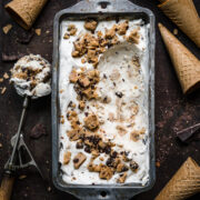 overhead view of vegan cookie dough ice cream in antique tin with ice cream cones around it.