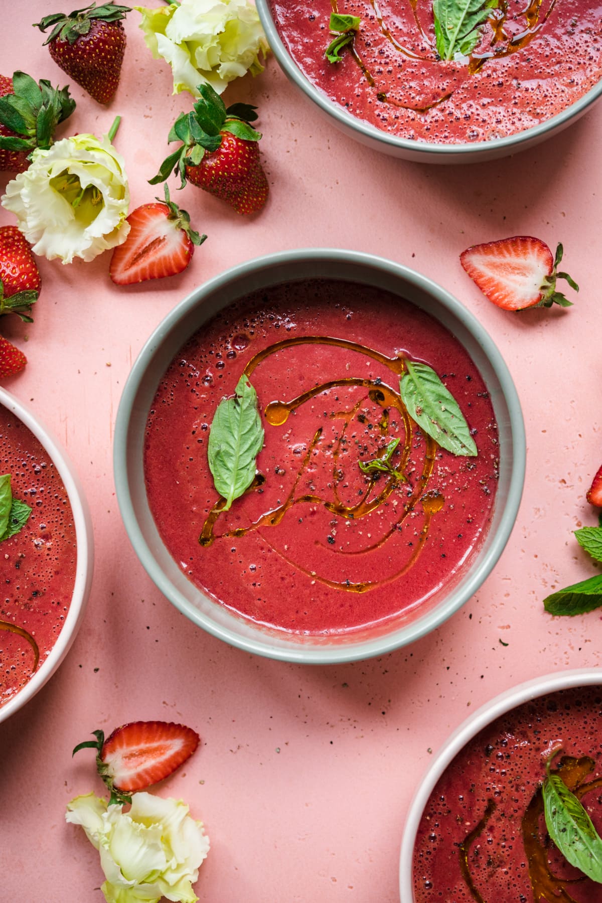 close up overhead view of strawberry watermelon gazpacho in light green bowl topped with fresh basil.