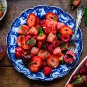 close up overhead view of watermelon berry salad on blue china plate with fork.