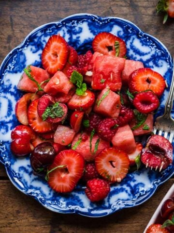 close up overhead view of watermelon berry salad on blue china plate with fork.