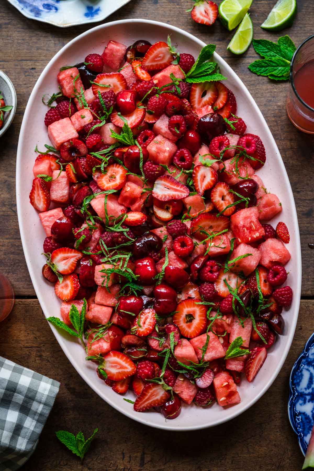 overhead view of watermelon berry salad with mint on a large platter on wood table. 