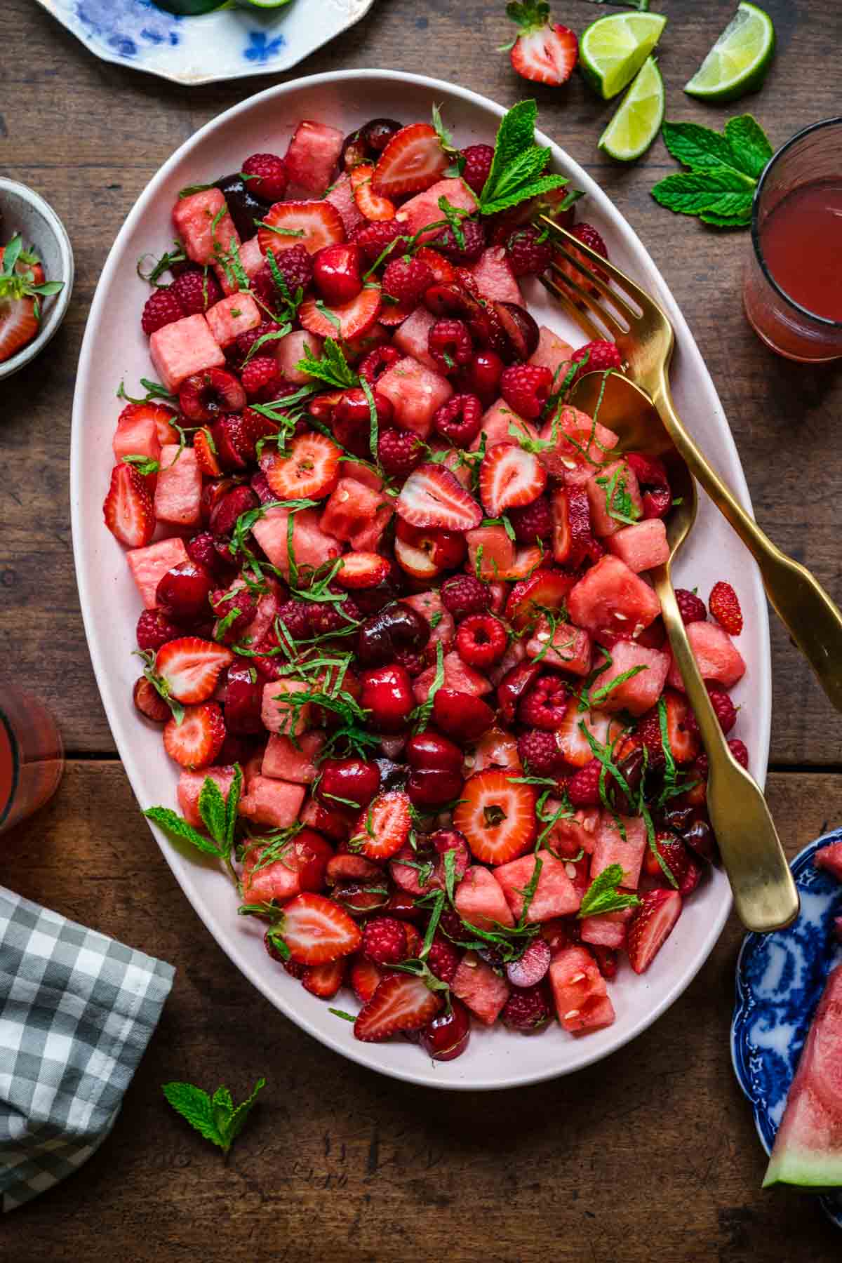 overhead view of watermelon berry salad with mint on a large platter on wood table. 