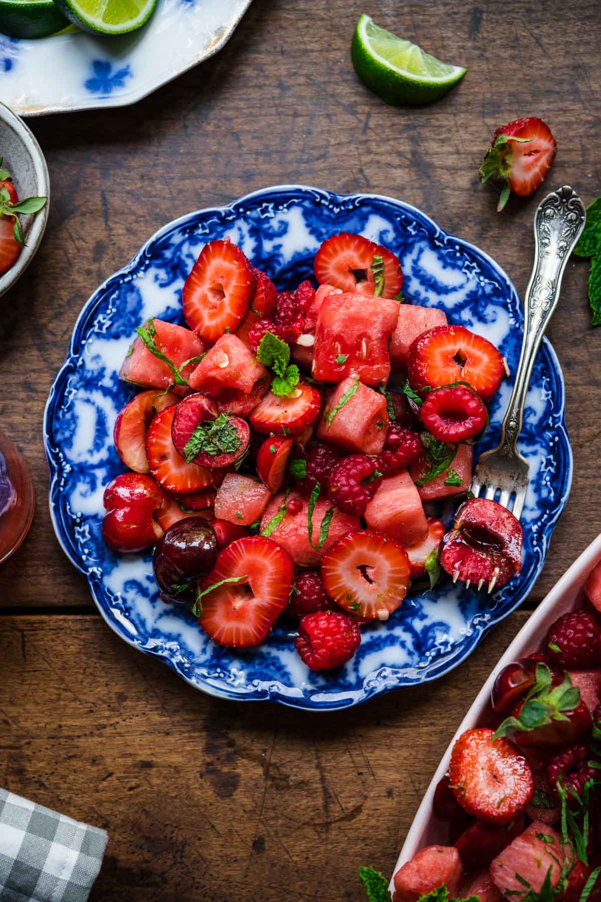 close up overhead view of watermelon berry salad on blue china plate with fork. 