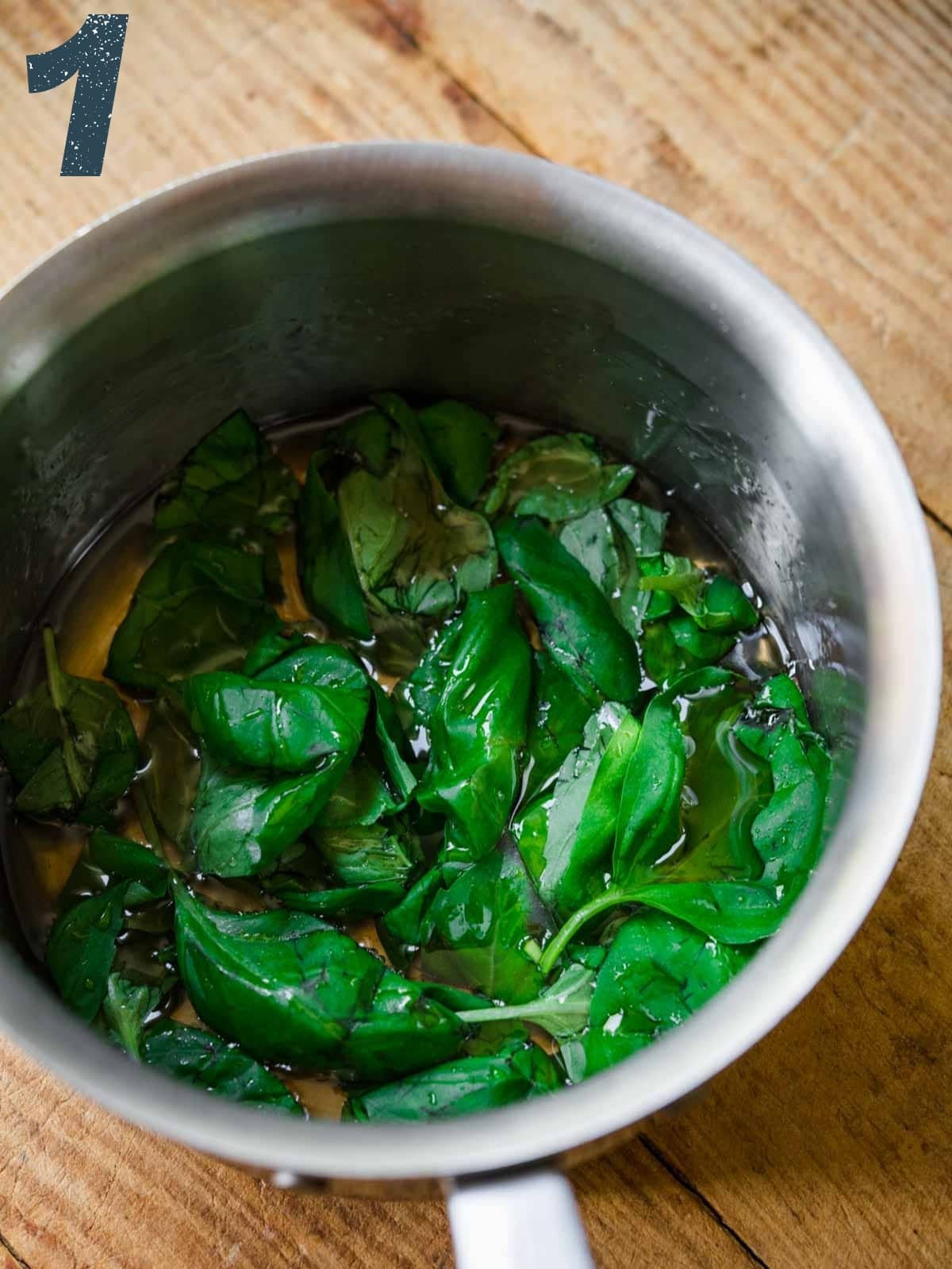 close up view of basil simple syrup in pot. 