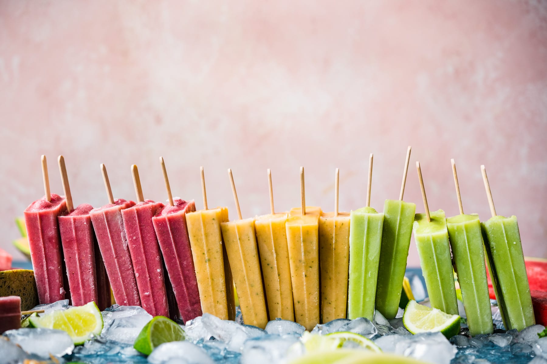 side view of stacked watermelon, cantaloupe and honeydew melon yogurt popsicles.