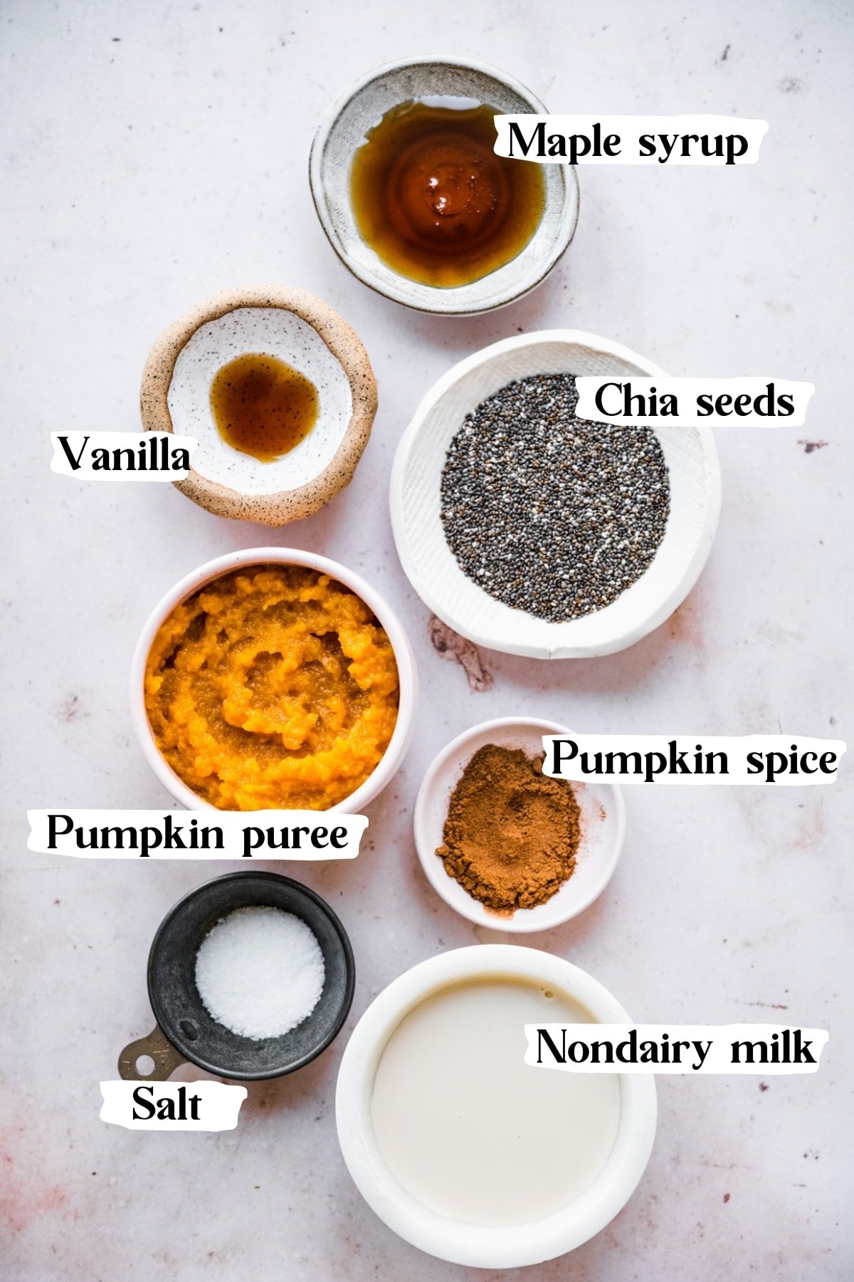 overhead view of ingredients for vegan pumpkin chia pudding in small prep bowls with text labels. 