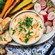 close up overhead view of sriracha white bean dip on a platter with fresh vegetables.
