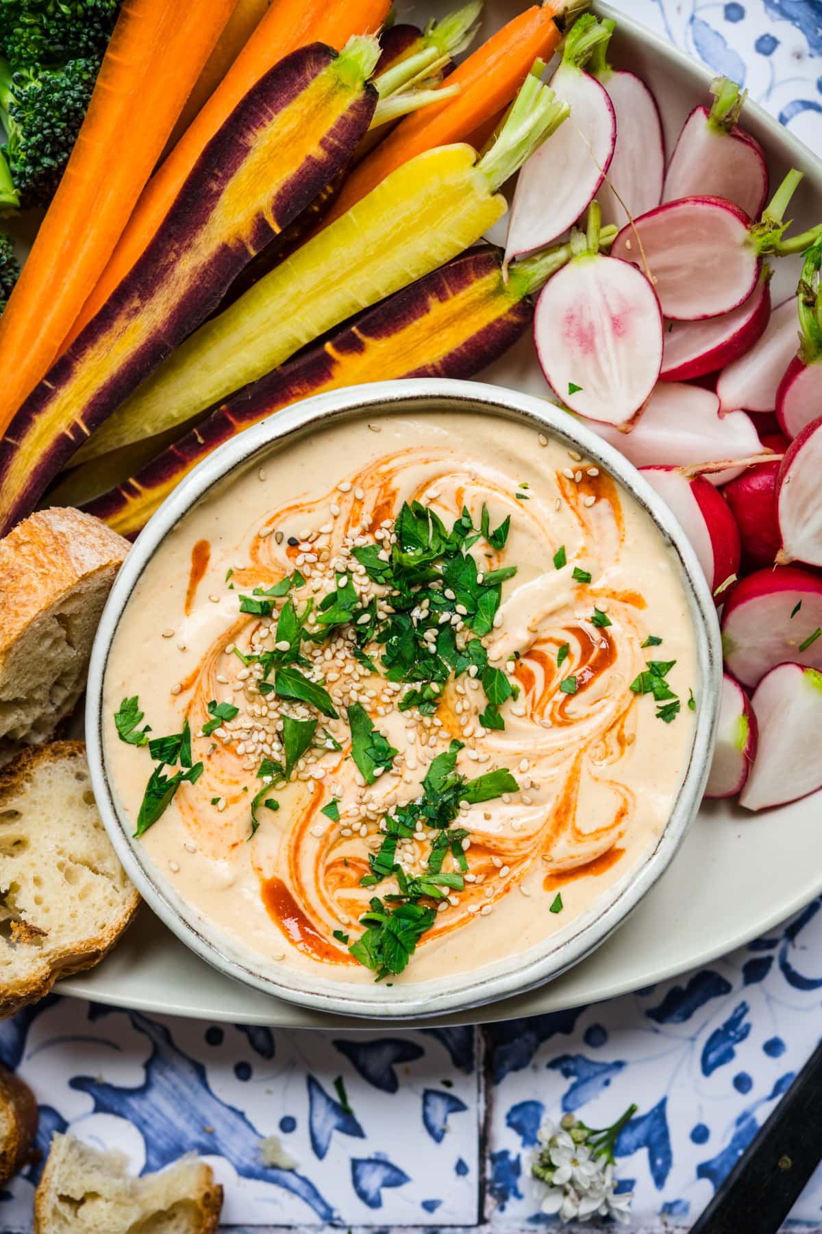 close up overhead view of sriracha white bean dip on a platter with fresh vegetables.