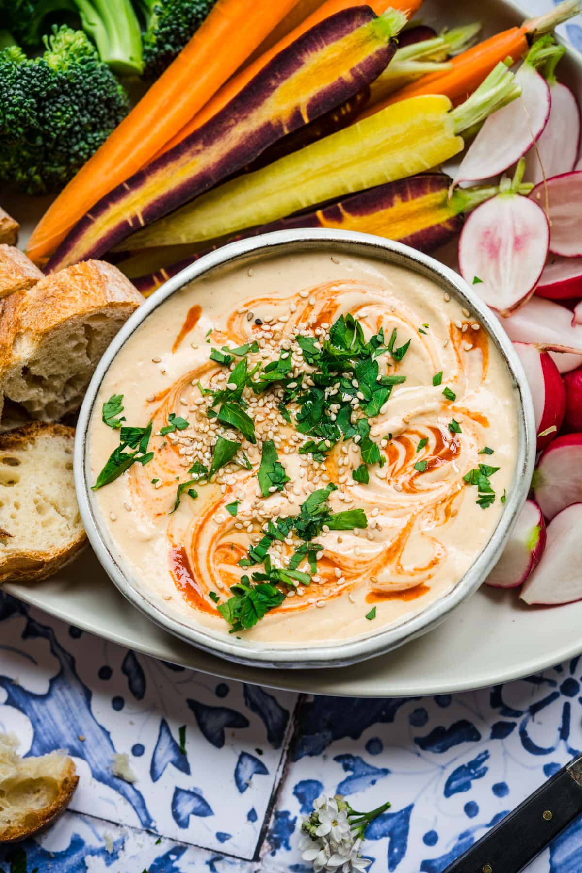 close up overhead view of sriracha white bean dip on a platter with fresh vegetables. 