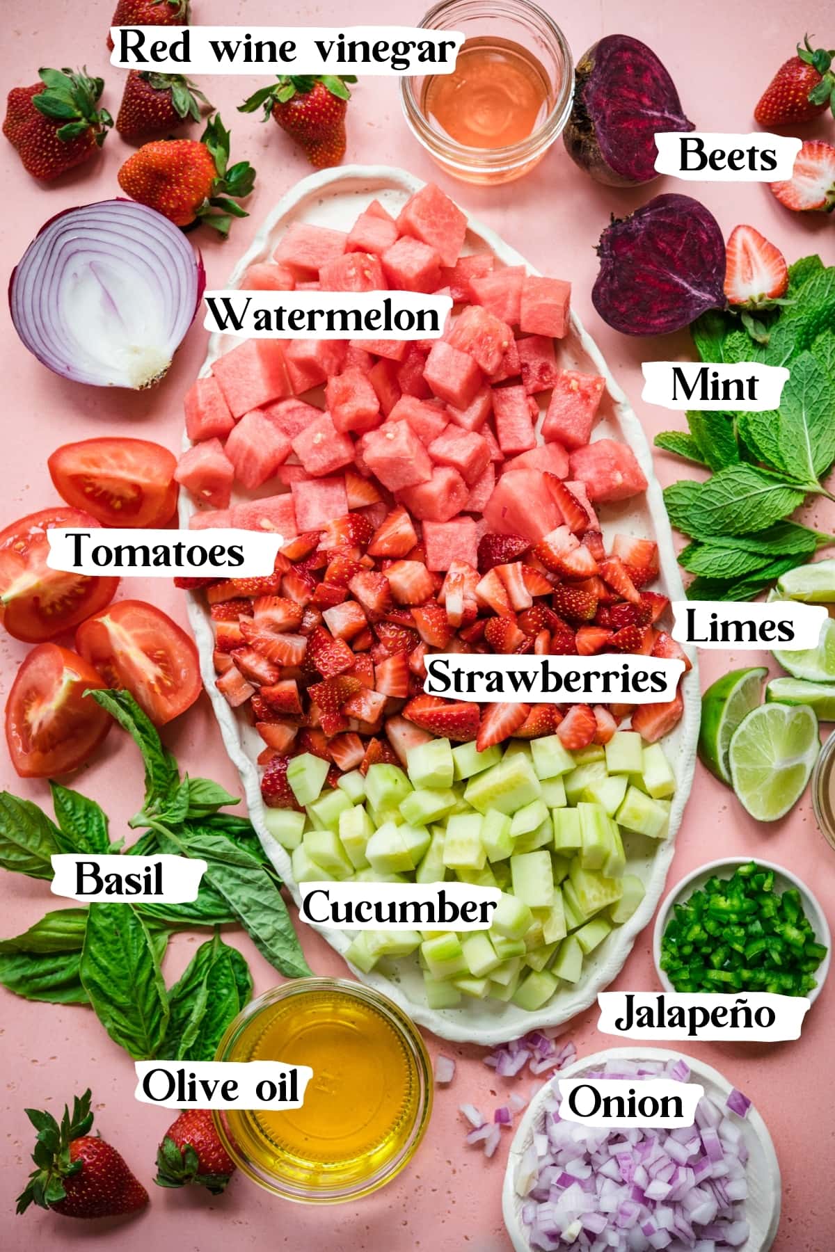 overhead view of ingredients laid out for strawberry watermelon gazpacho on platter and small bowls. 