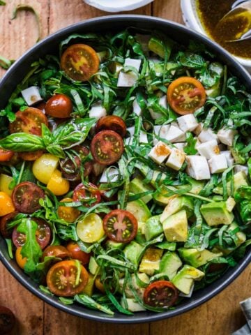 Overhead view of arugula caprese salad in a bowl.