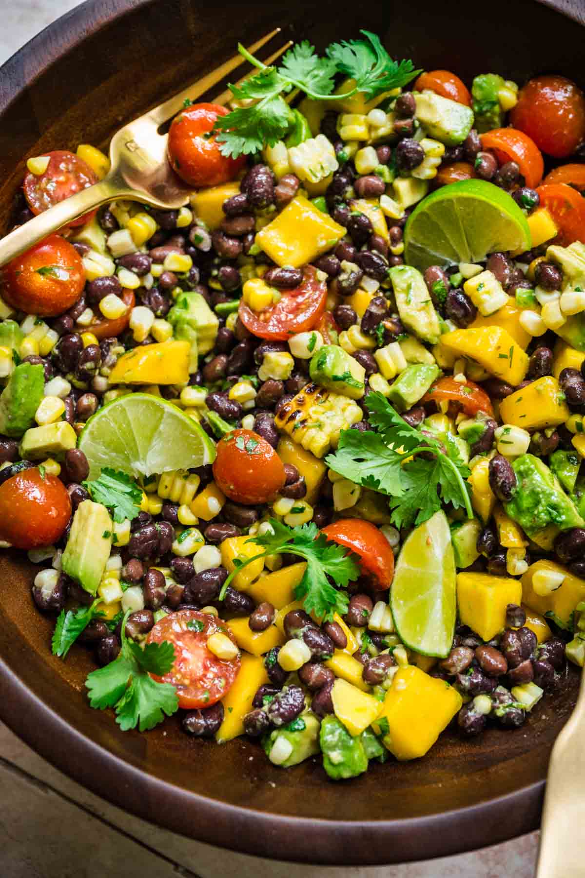 Close up of mango salad with black beans, cilantro, mango, tomatoes, and lime.