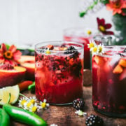 side view of blackberry peach cocktail with summer flowers.