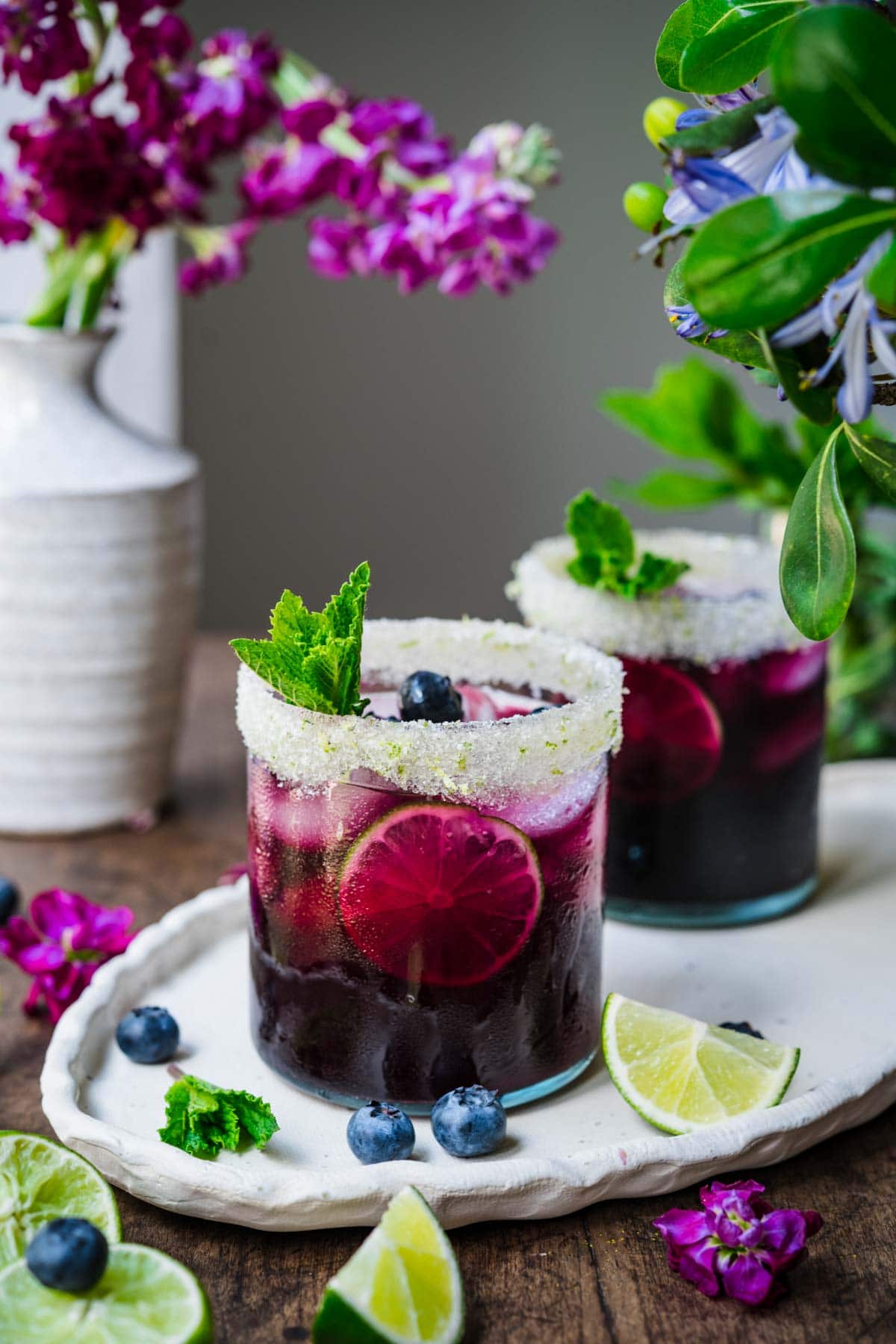 Front view of blueberry. margarita in a glass, garnished with mint.