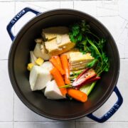 Pot full of corn, onions, parsley, carrots, and peppers.