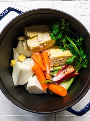 Pot full of corn, onions, parsley, carrots, and peppers.