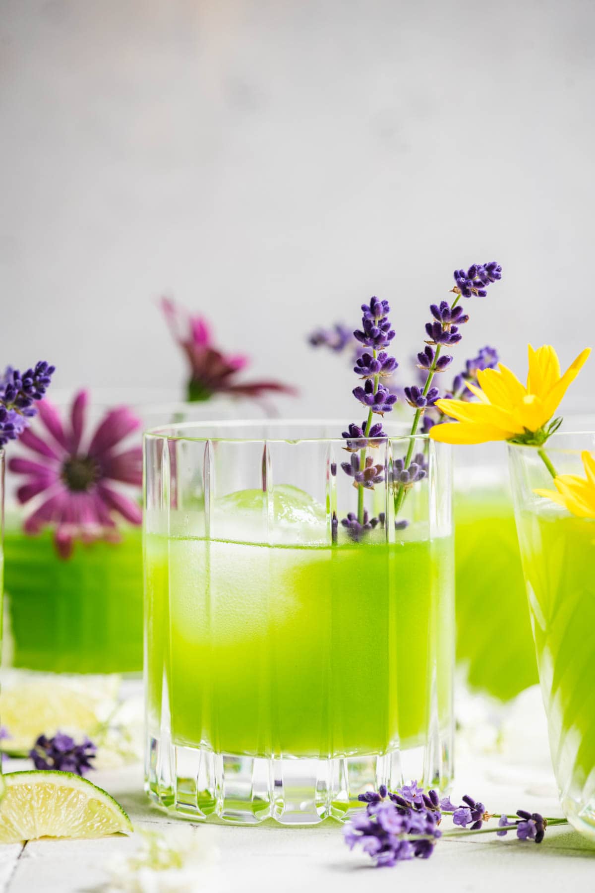 Cucumber gin cocktail in a glass with ice, garnished with a sprig of lavender.