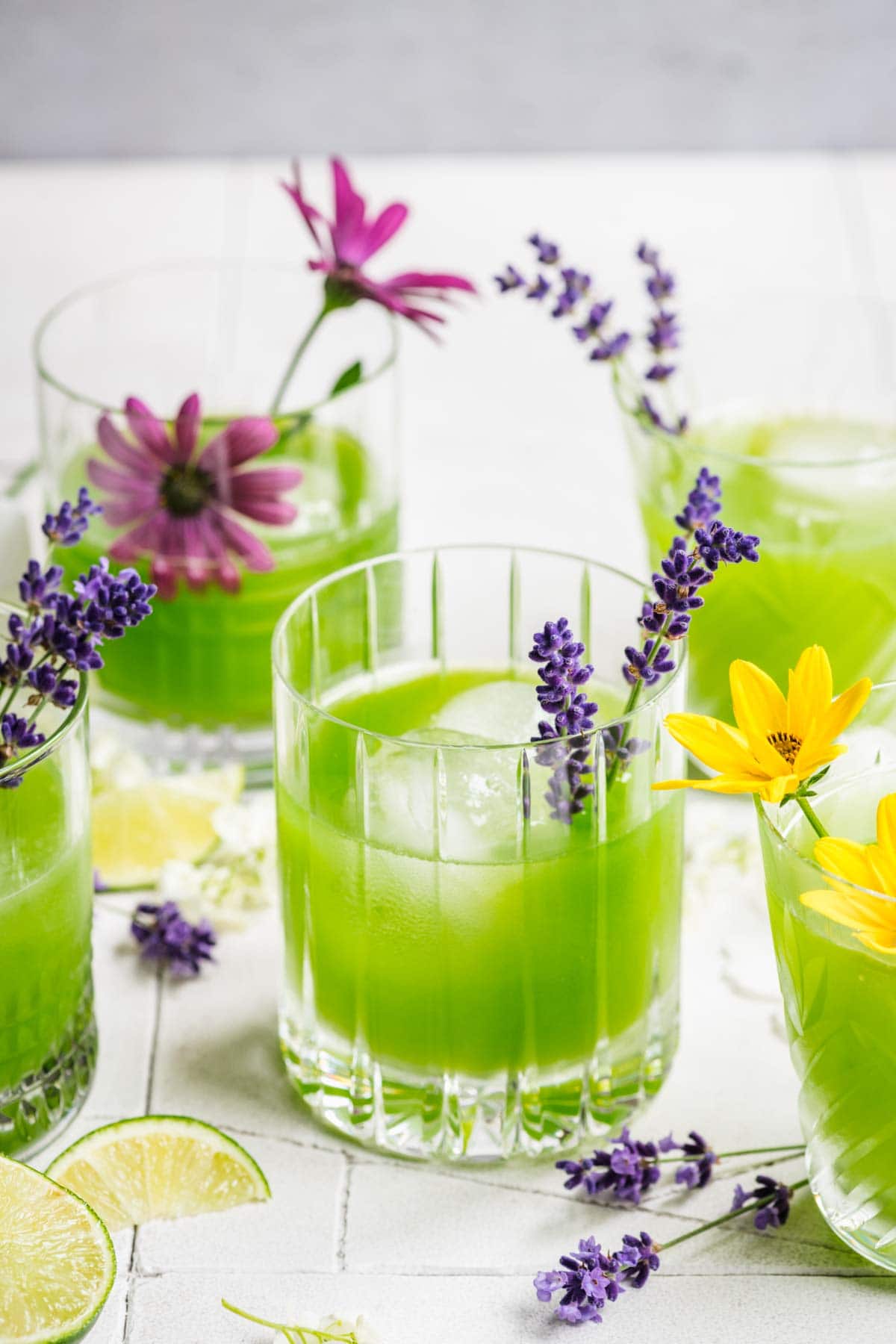 Cucumber gin cocktail in a glass with ice, garnished with a sprig of lavender.