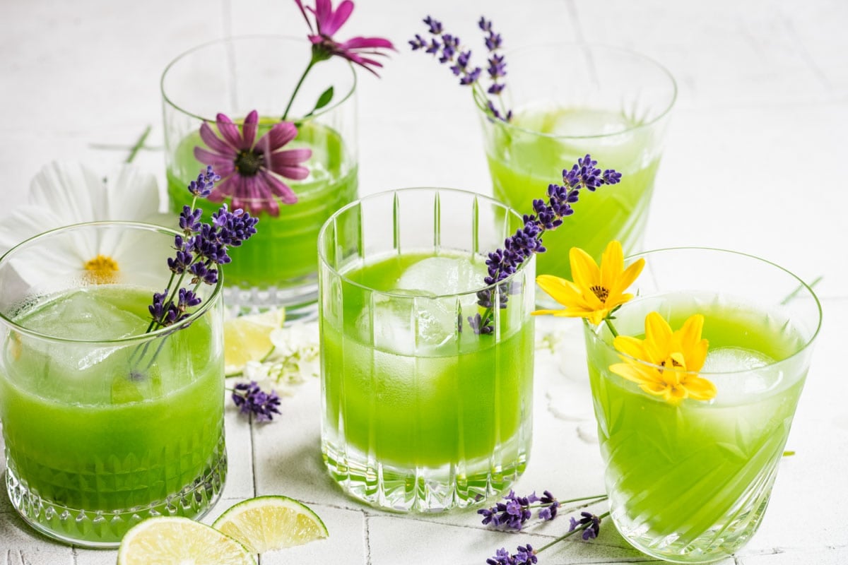 5 cucumber cocktails in varied glasses, garnished with flowers.