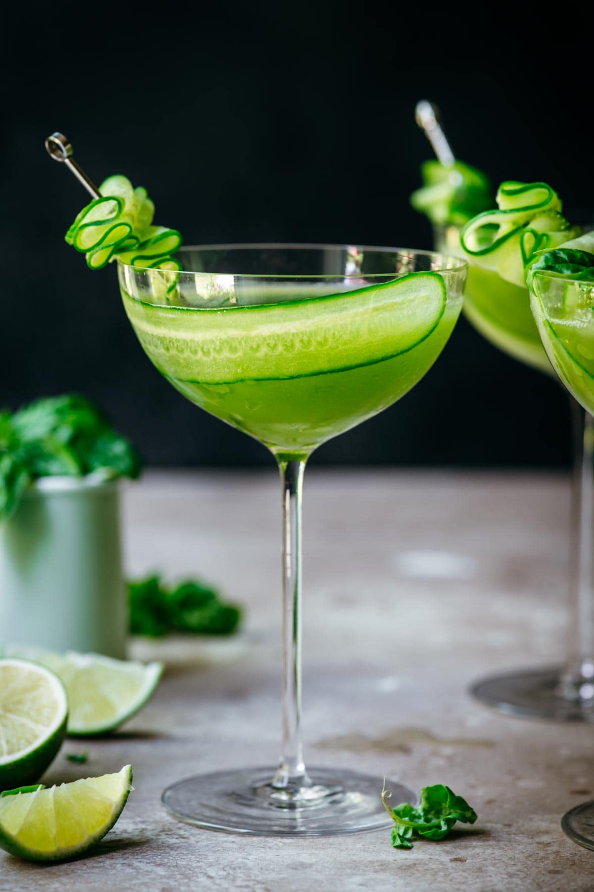 Front view of cucumber martini in a martini glass, garnished with cucumber.