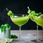 Front view of cucumber martini in a glass garnished with a slice of cucumber.