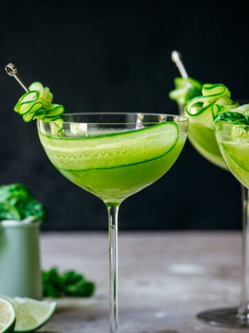 Front view of cucumber martini in a glass garnished with a slice of cucumber.