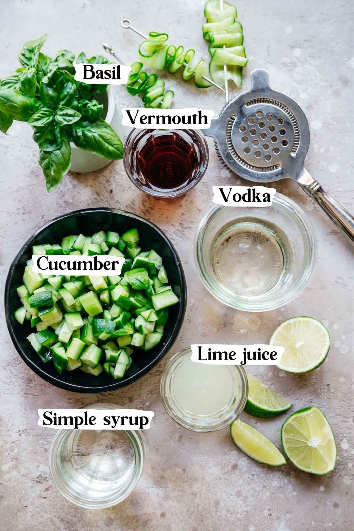 Overhead shot of ingredients needed in this recipe, including vodka, cucumber, simple syrup, basil, and vermouth.