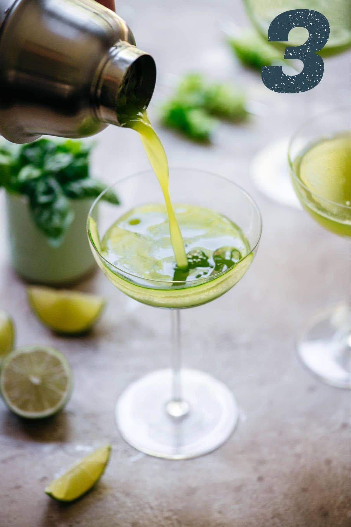 Cucumber martini being poured out of cocktail shaker into a martini glass.