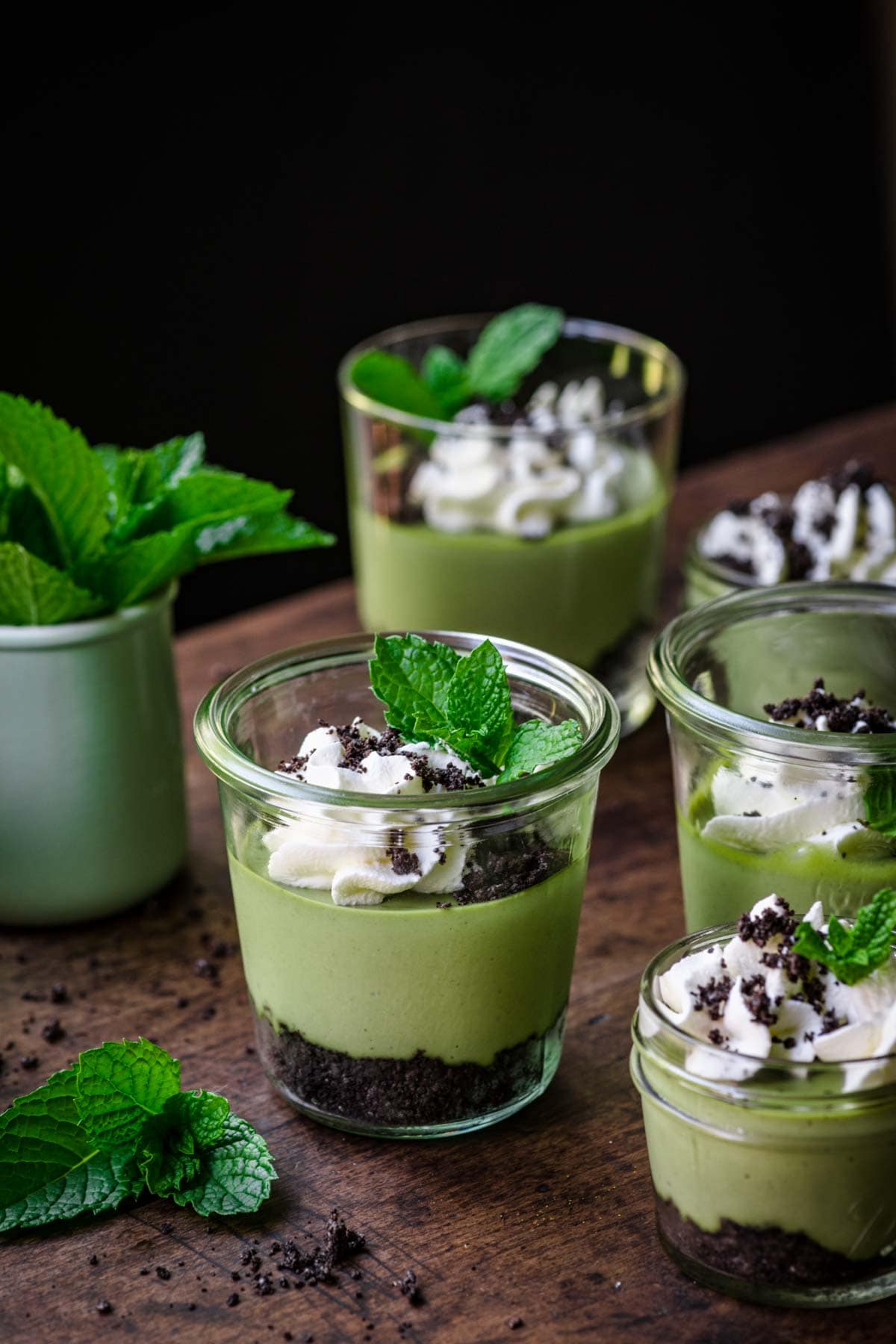 Front view of mini green cheesecake in a jar with a whipped cream and mint garnish.