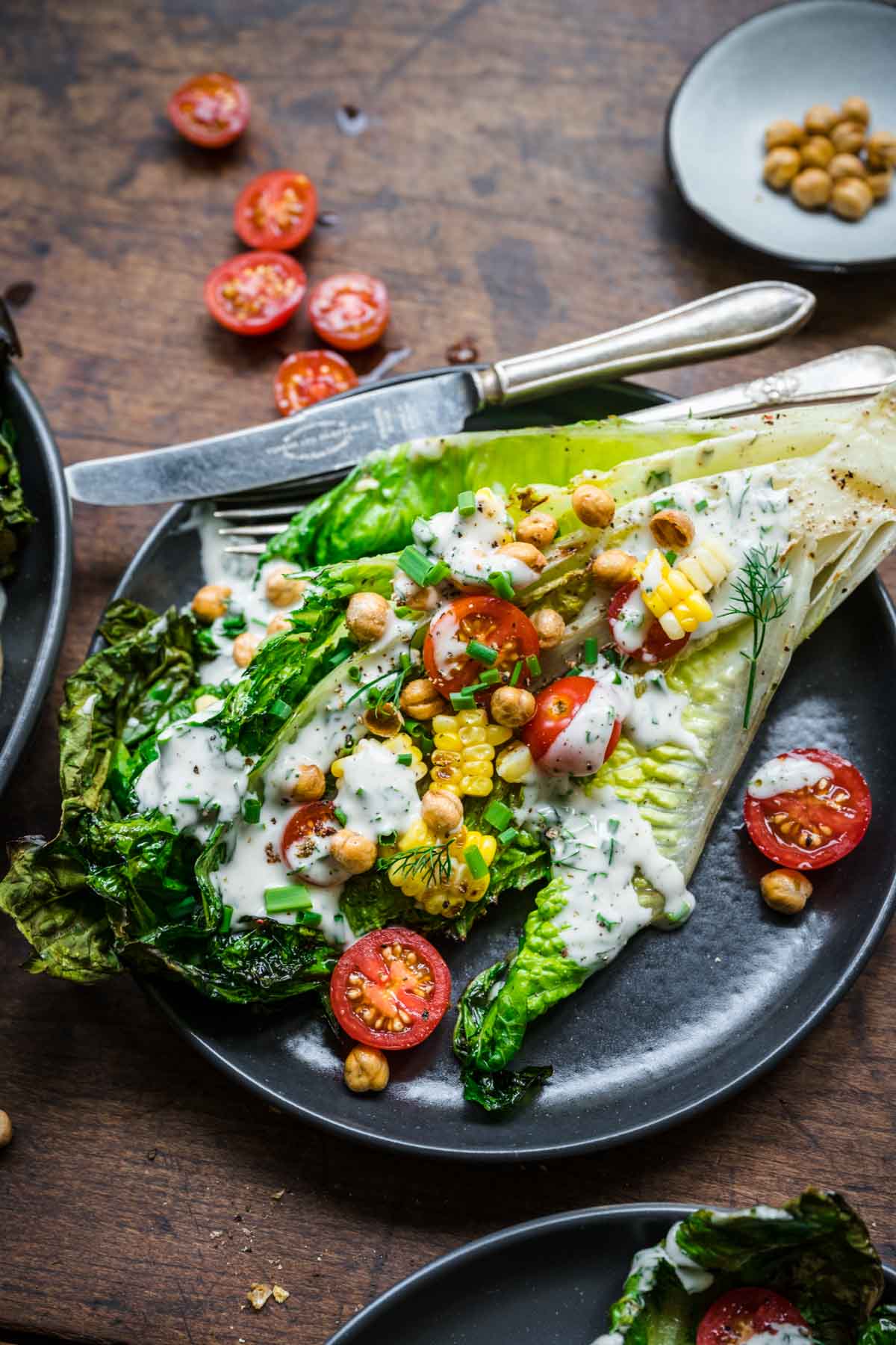 Overhead view of grilled romaine with corn, tomatoes, and vegan ranch dressing.