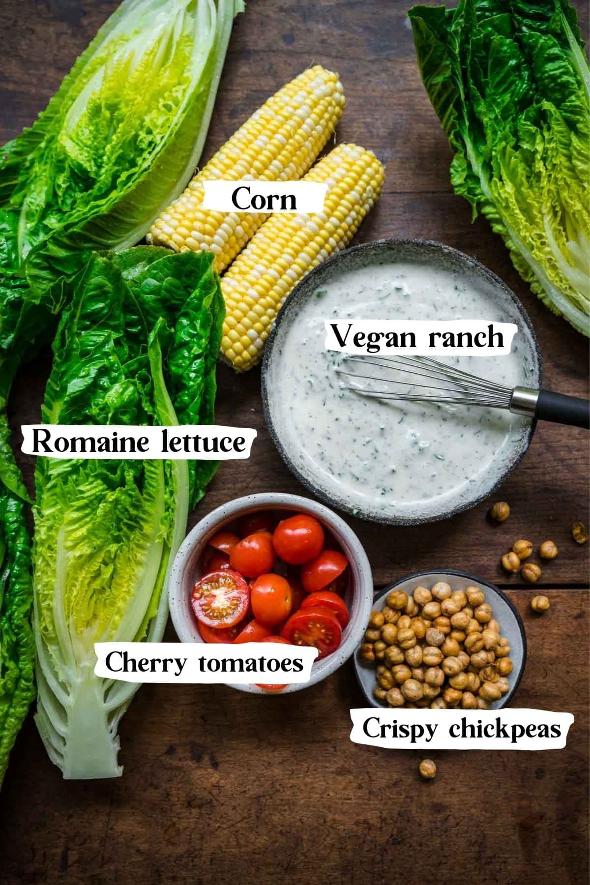 Overhead picture of the ingredients in this salad: romaine, corn, cherry tomatoes, crispy chickpeas, vegan ranch dressing.