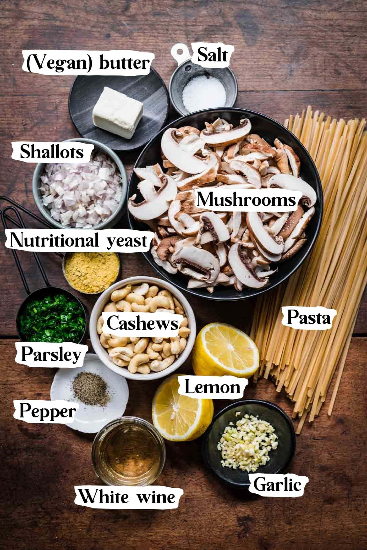 Overhead view of mushroom alfredo ingredients, including pasta, mushrooms, cashews, and parsley.