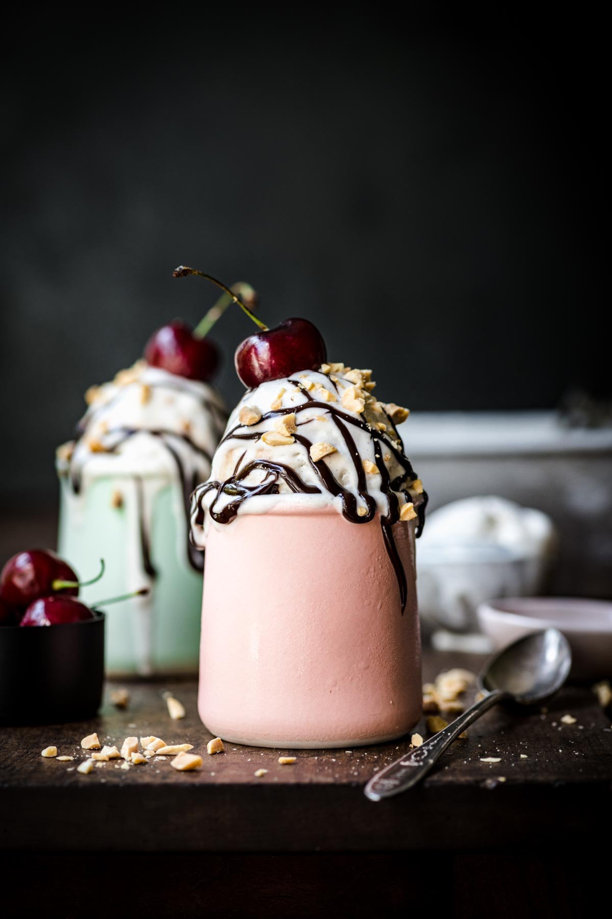 Front view of ice cream in a small jar with a drizzle of chocolate and sprinkle of chopped nuts.