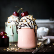 Front view of vanilla ice cream with chocolate nuts a cherry for garnish.