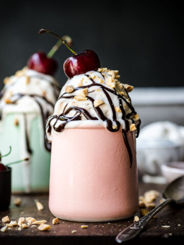 Front view of vanilla ice cream with chocolate nuts a cherry for garnish.