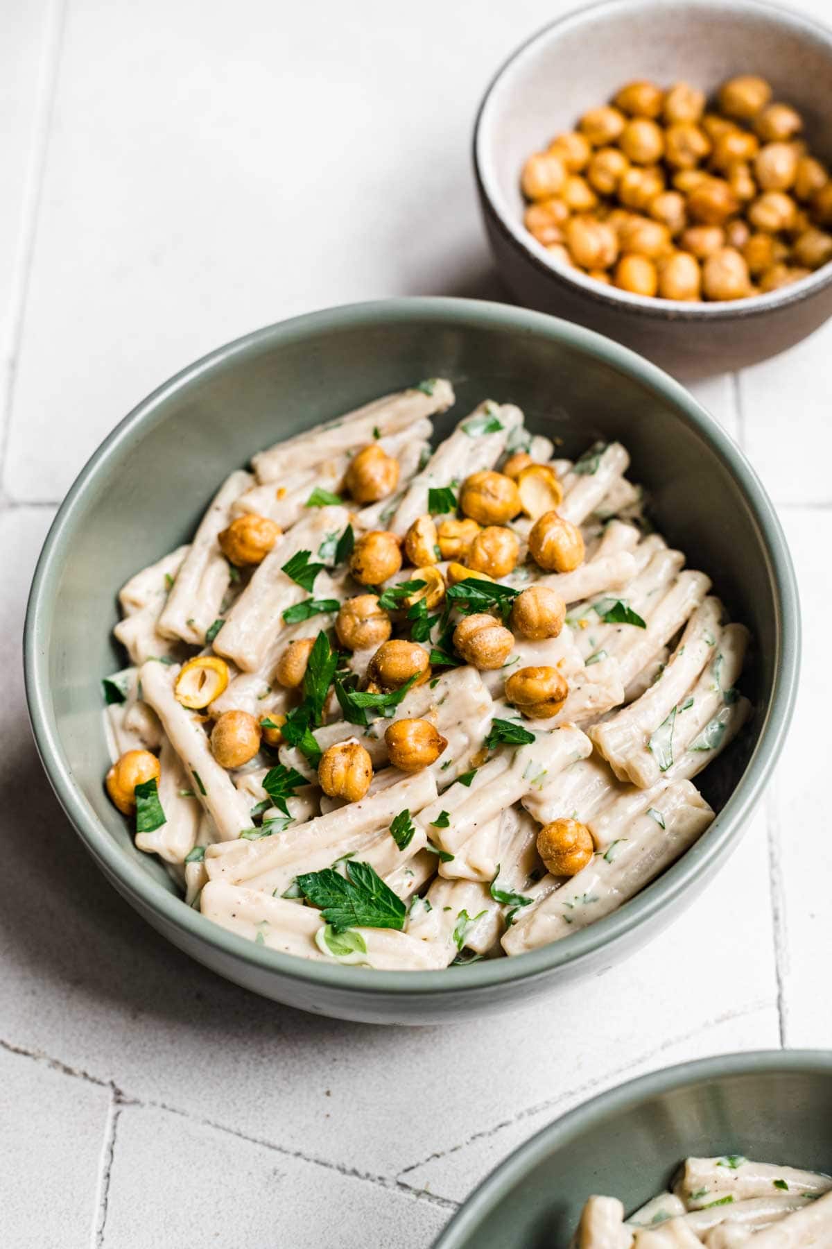 Overhead view of tahini pasta garnished with herbs and crispy chickpeas.