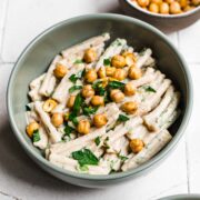 Overhead view of tahini pasta garnished with herbs and crispy chickpeas.