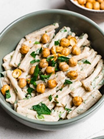 Overhead view of tahini pasta garnished with herbs and crispy chickpeas.