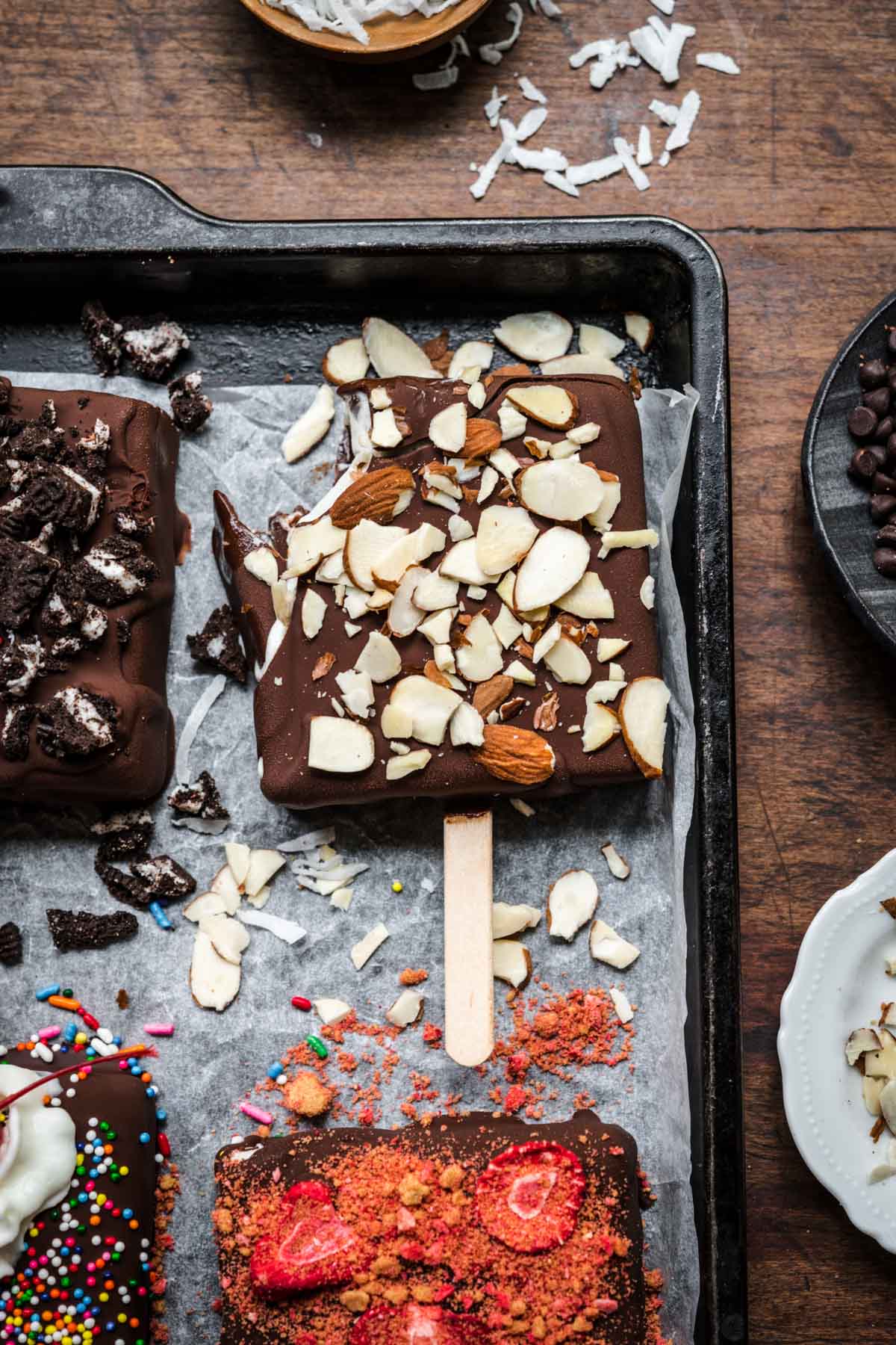 close up view of vegan ice cream bar with almonds on top with bite taken out. 