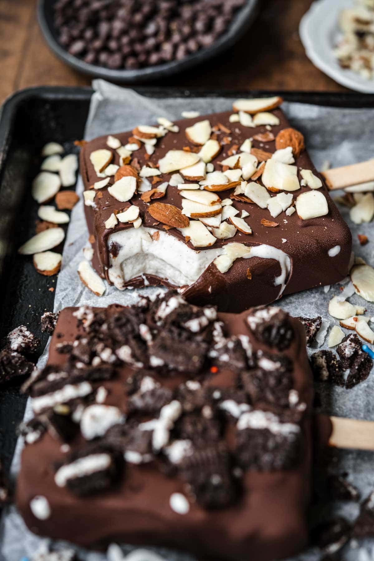 close up view of vegan ice cream bar with almonds on top with a bite taken out. 